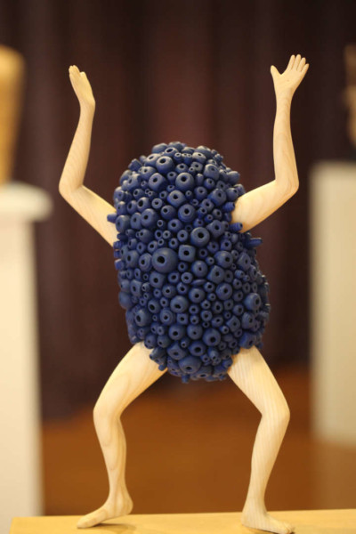 Arrêtez tout ! - François LACOSTE Sculpture en bois : bras et jambes émergeant d'un nuage de perles bleu