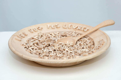 Bouillon de lecture - François LACOSTE Sculpture en bois d'une assiette contenant des lettres avec une cuillère