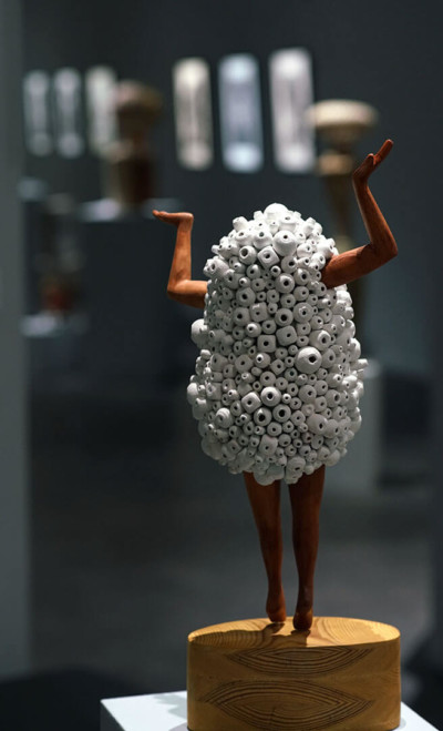 Cumulo-dubitatif - François LACOSTE Sculpture en bois : bras et jambes émergeant d'un nuage de perles blanches dans une attitude dubitative
