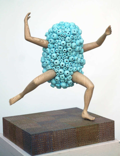 Une énergie en bleu - François LACOSTE Sculpture en bois : bras et jambes émergeant d'un nuage de perles bleues dans une attitude dynamique