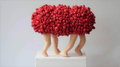 La toute première - François LACOSTE Sculpture en bois : 4 jambes émergeant d'un nuage de perles rouges et avançant dans le même sens