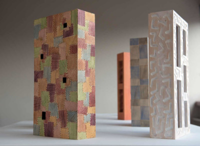 Boîtes de la série Corbu-extrapolations - François LACOSTE 4 sculptures en bois en forme de boîte exposées sur une table
