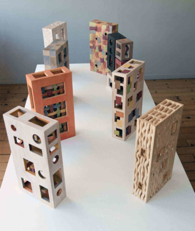 Boîtes Corbu-extrapolations - François LACOSTE 8 sculptures en bois en forme de boîte exposées sur une table